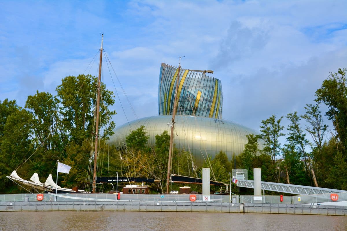 La Cité du Vin à Bordeaux vue depuis la Garonne, avec des bateaux à quai
