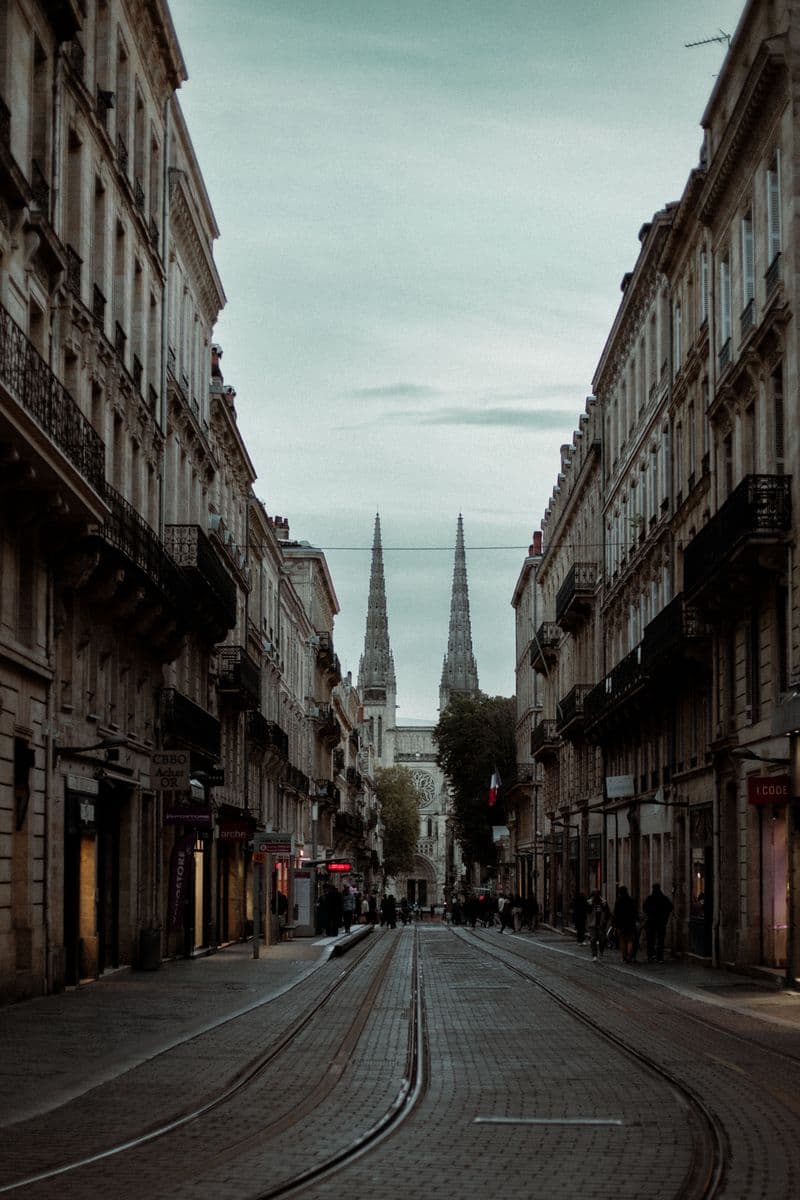 Rue Vital-Carles à Bordeaux : rails du tramway, immeubles en pierre et flèches de la cathédrale Saint-André