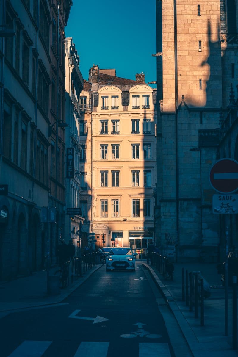 Rue étroite à sens unique de Lyon, une voiture entre de hauts immeubles anciens