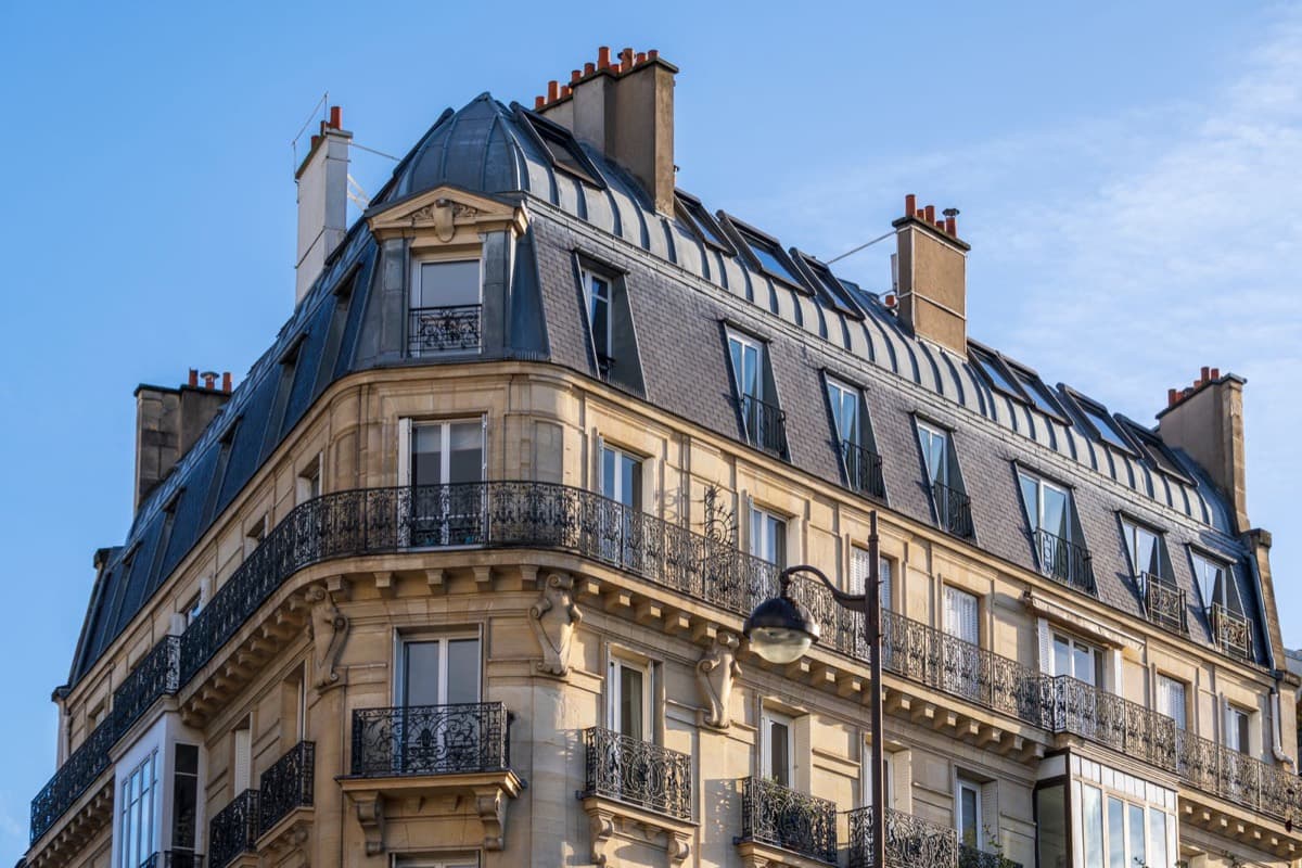 Façade d'un immeuble haussmannien à Paris : balcons en fer forgé et toit mansardé