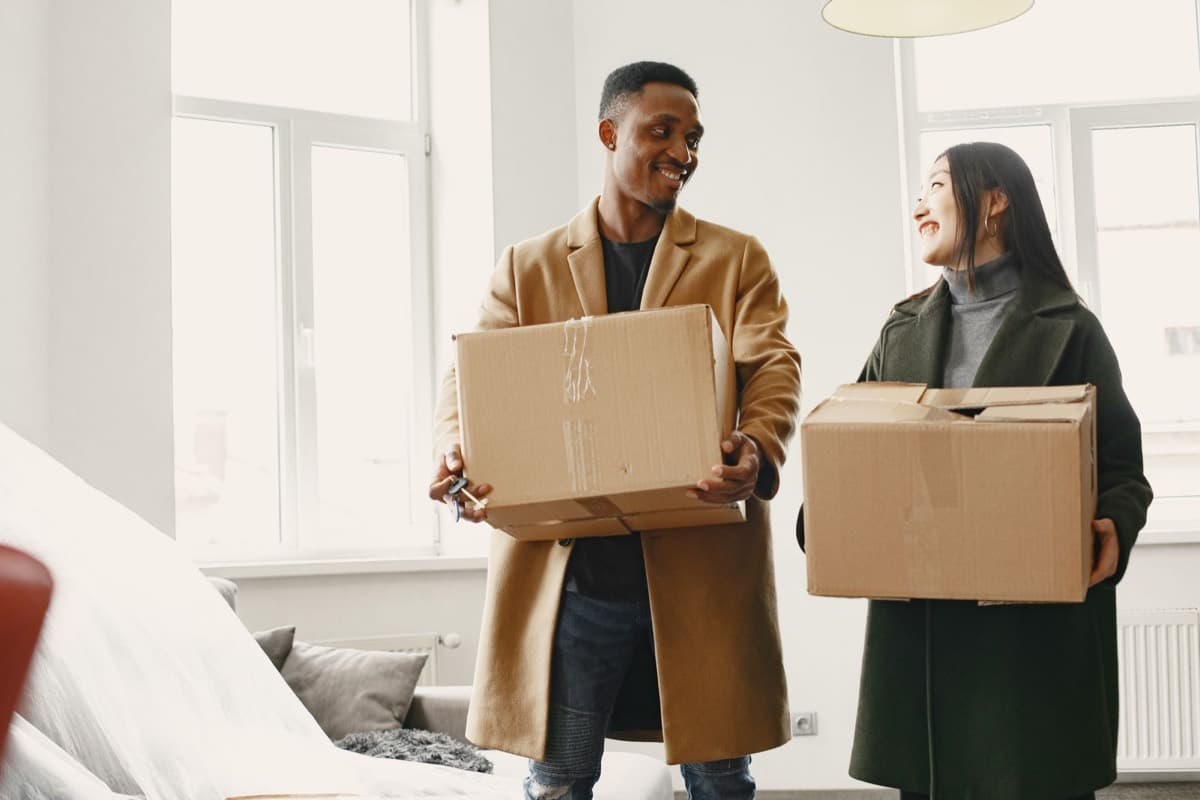 Couple portant des cartons de déménagement dans leur nouveau logement