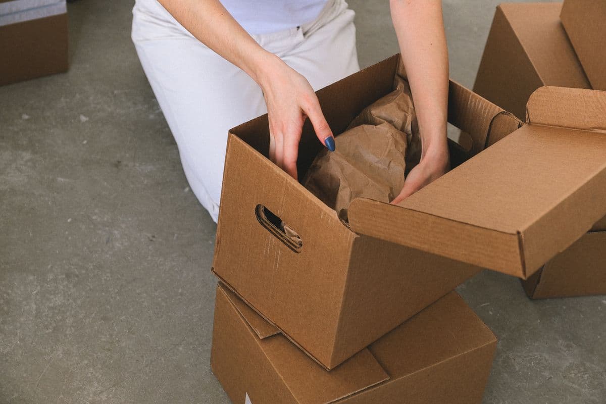 Mains d'une personne rangeant des objets emballés dans un carton