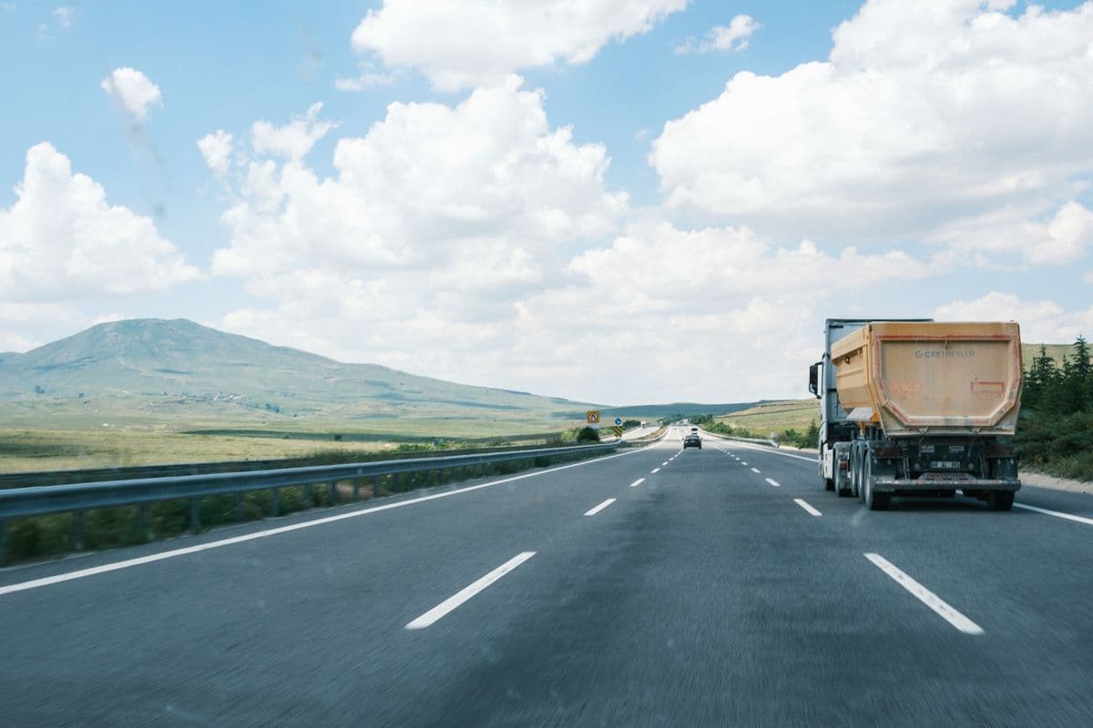 Camion sur une autoroute dégagée sous un ciel bleu, collines au loin